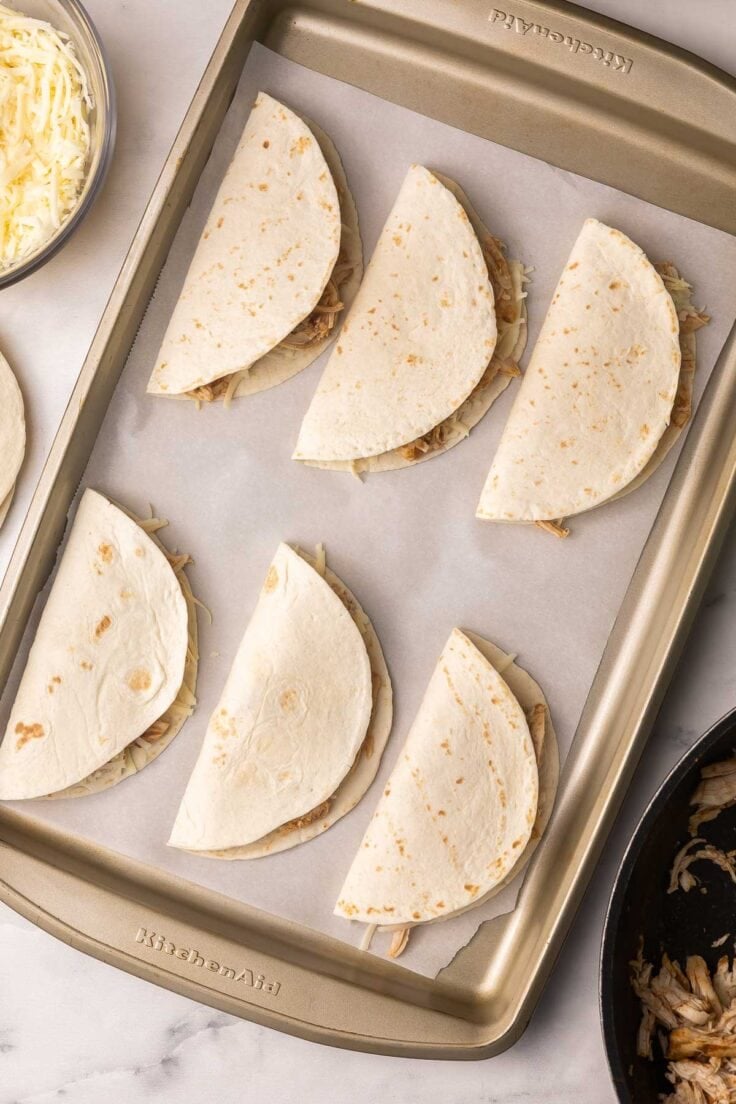 small chicken tacos on baking sheet ready to bake.