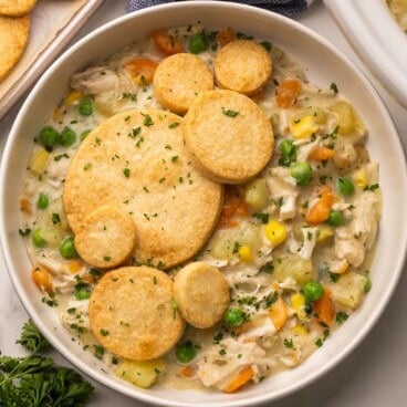 close up of a bowl of crockpot chicken pot pie with biscuits on top.