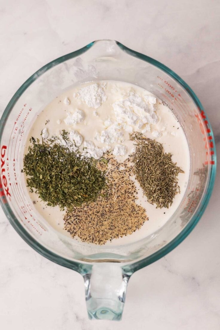 glass measuring cup filled with cream and spices added.