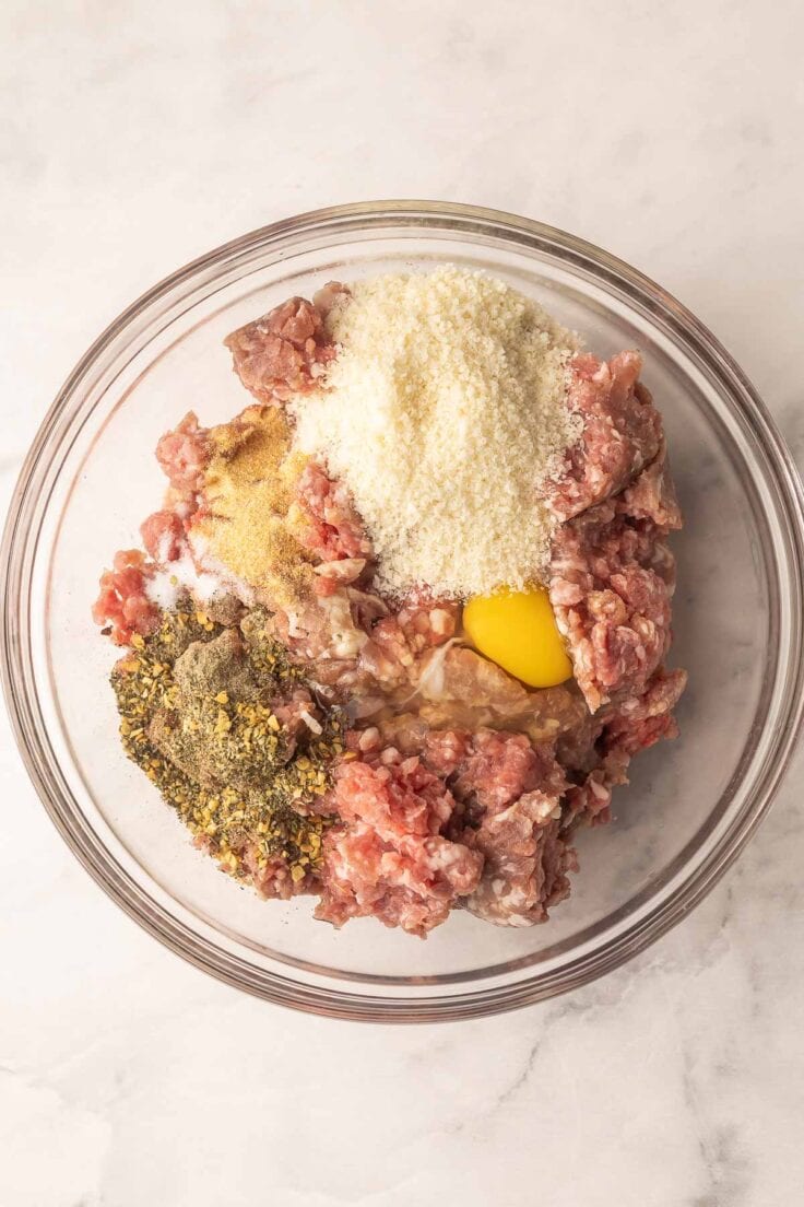 unmixed meatloaf ingredients in a glass mixing bowl.