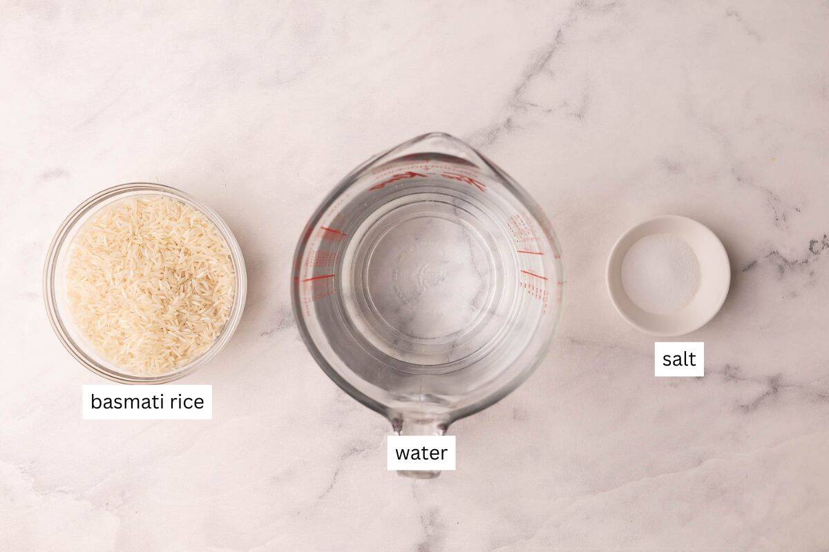 This Perfect Basmati Rice recipe is light, fluffy and never sticky! It takes just 20 minutes and comes out beautifully every single time. #rice #recipe #dinner | dinner recipes | easy recipes | how to cook rice | how to make rice | how to cook basmati rice | basmati rice recipe ingredients needed to cook basmati rice on a white marble background.