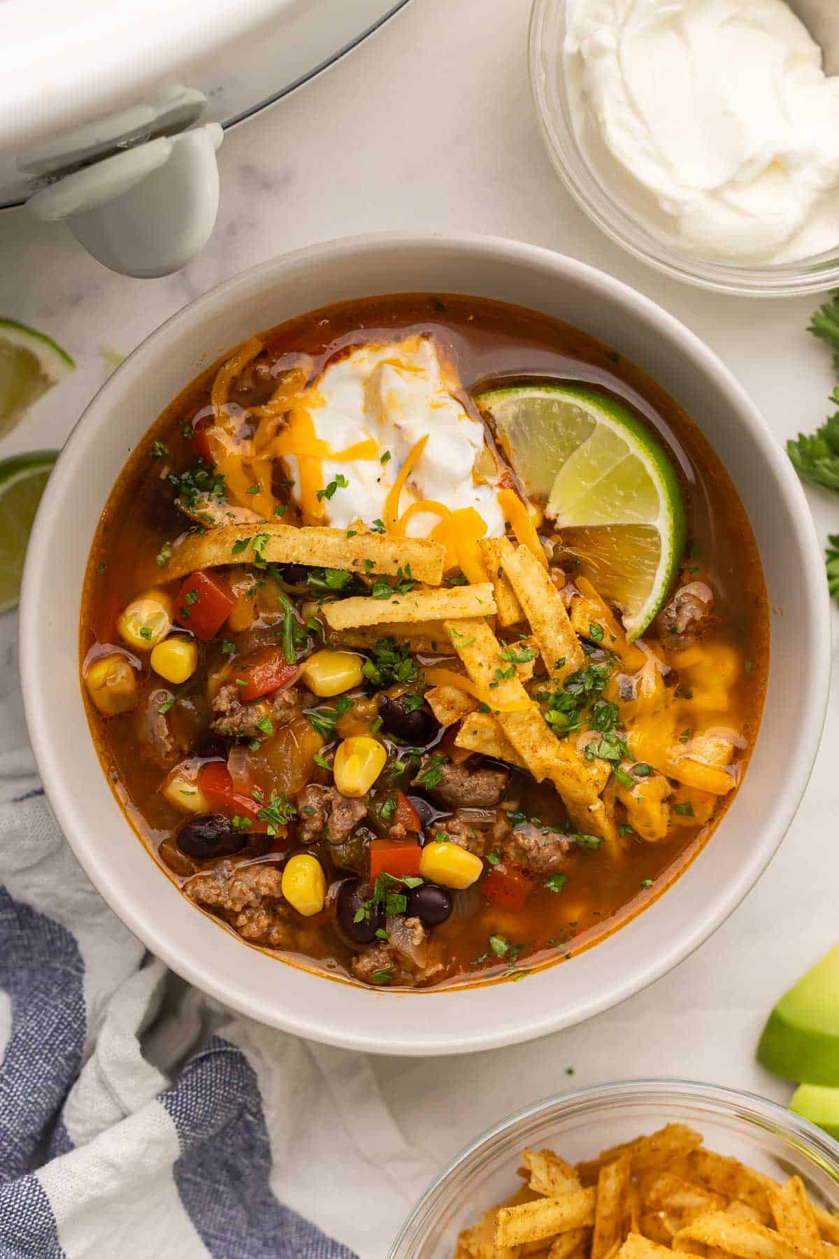 This Slow Cooker Taco Soup is an easy crockpot meal that's packed with flavor! Just 15 minutes of prep and the crockpot does the rest. Perfect for busy nights when you don't feel like cooking! #soup #dinner #recipe | soup recipes | slow cooker soup | crockpot soup | ground beef recipes overhead close up image of a bowl of slow cooker taco soup.