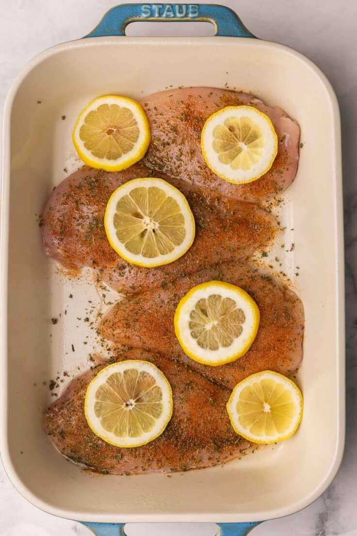 chicken breasts in a baking dish with lemon slices.