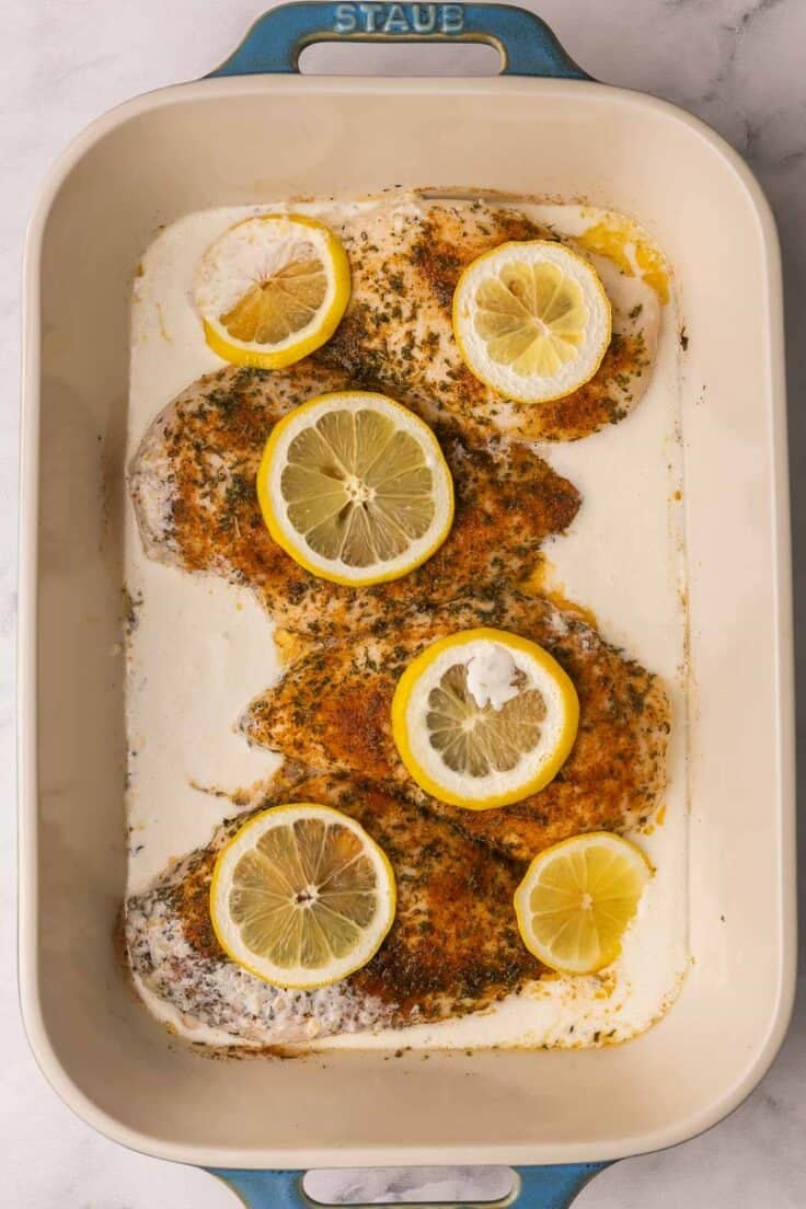 cream sauce added to lemon chicken in baking dish.