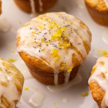 lemon poppy seed muffin with glaze and lemon zest on top.