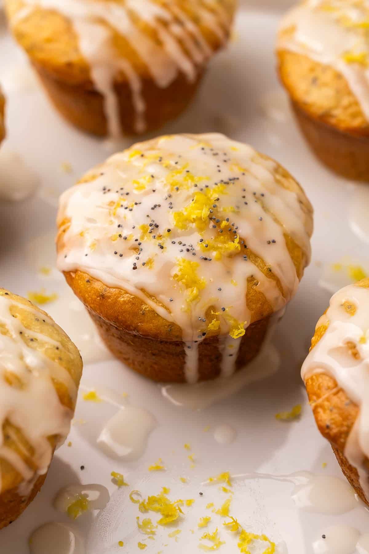 These fluffy Lemon Poppy Seed Muffins are light, zesty, and bakery-soft! Made with Greek yogurt for moisture and finished with a bright lemon glaze. #baking #recipe | muffin recipes | lemon recipes | baking from scratch | breakfast ideas | healthy snacks close up image of lemon poppy seed muffin with glaze on top.