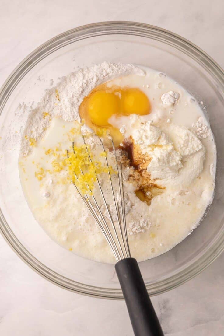 wet ingredients added for lemon pancakes in glass bowl.