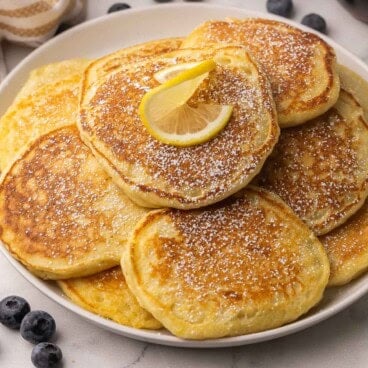 square image of a plate of lemon ricotta pancakes with powdered sugar.