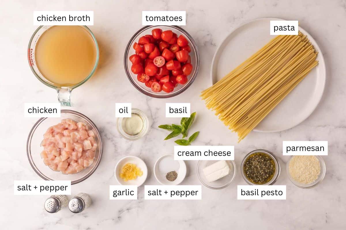 overhead image of tomato basil pasta with chicken on a marble background.