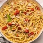 square overhead image of creamy tomato basil pasta with chicken in white braiser.