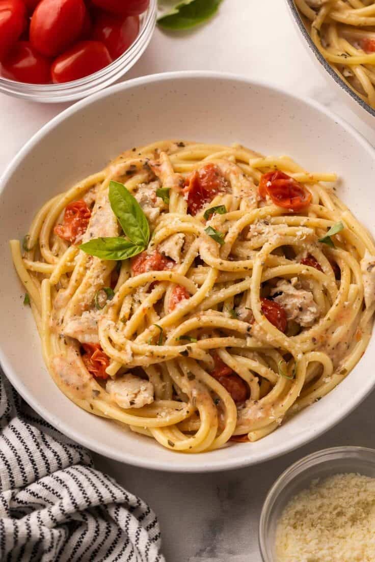 tomato basil chicken pasta in a shallow beige bowl.