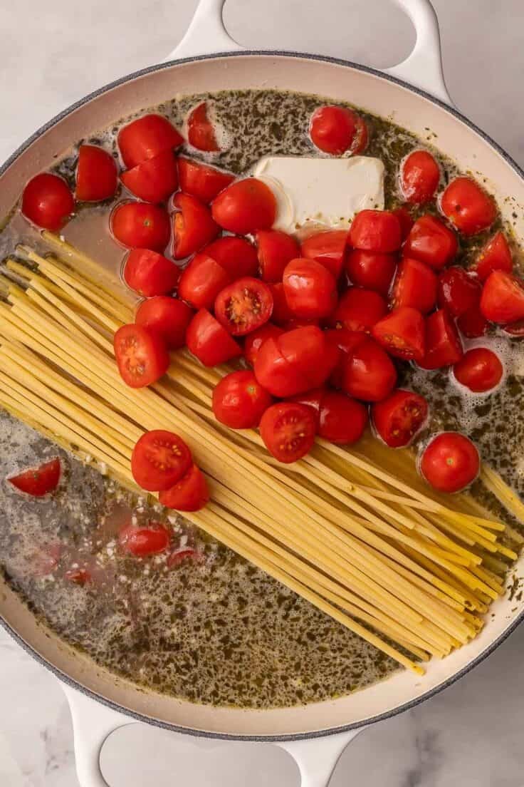 uncooked noodles and fresh tomatoes added to the skillet with the broth.