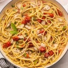 overhead image of creamy tomato pasta with chicken and basil in a white braiser.