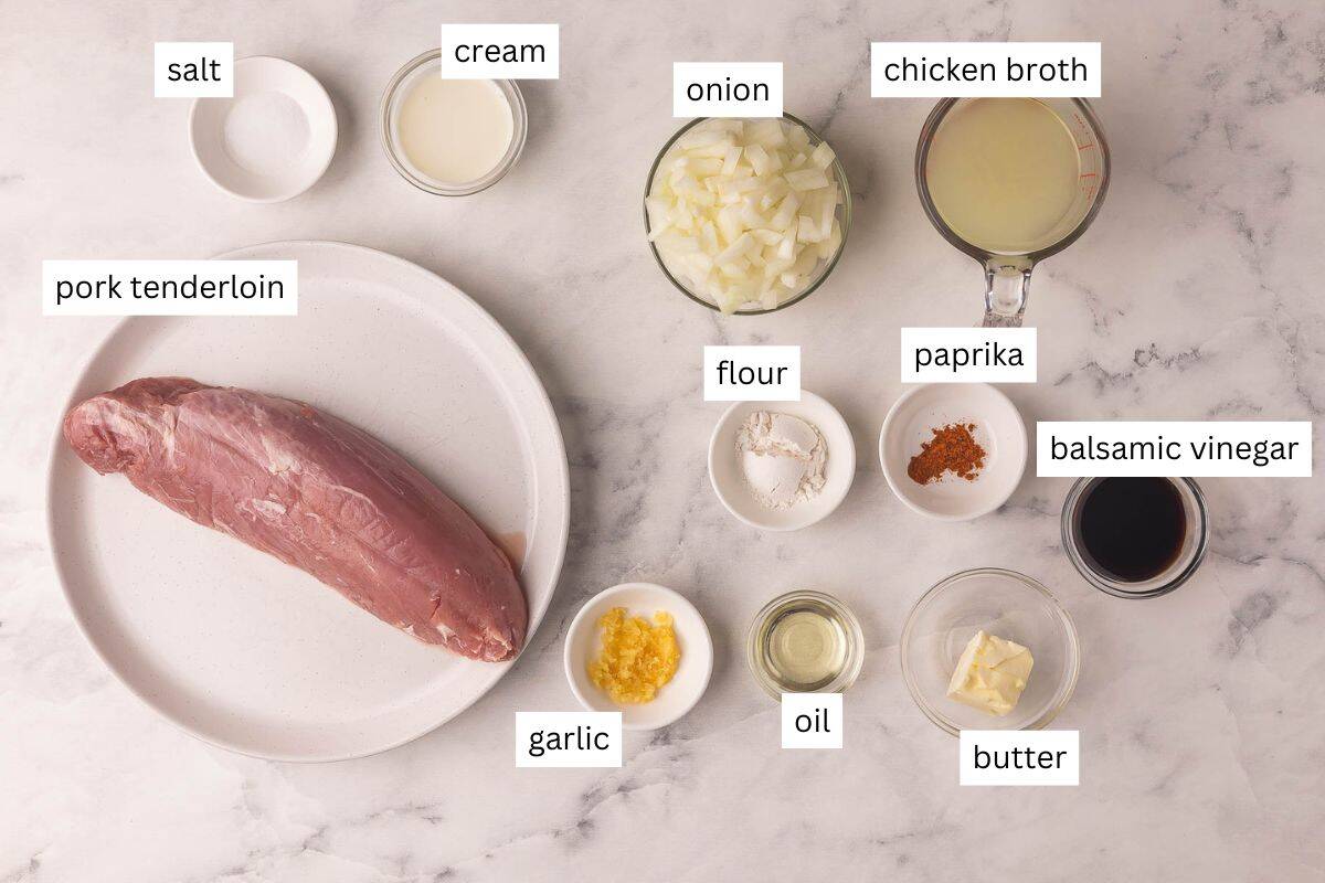 These Pork Medallions with Balsamic Onion Gravy are full of flavor, with a perfectly seasoned creamy gravy with sautéed onions and a touch of vinegar. Ready in 30 minutes with simple ingredients and one skillet! #pork #dinner #recipe | easy dinner ideas | pork tenderloin recipes | easy dinner | comfort food | pork with gravy | ingredients needed for pork tenderloin medallions on a white marble background.