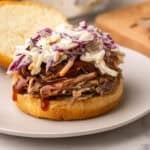 square image of a pulled pork sandwich with coleslaw and no top bun.