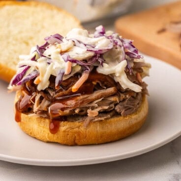 square image of a pulled pork sandwich with coleslaw and no top bun.
