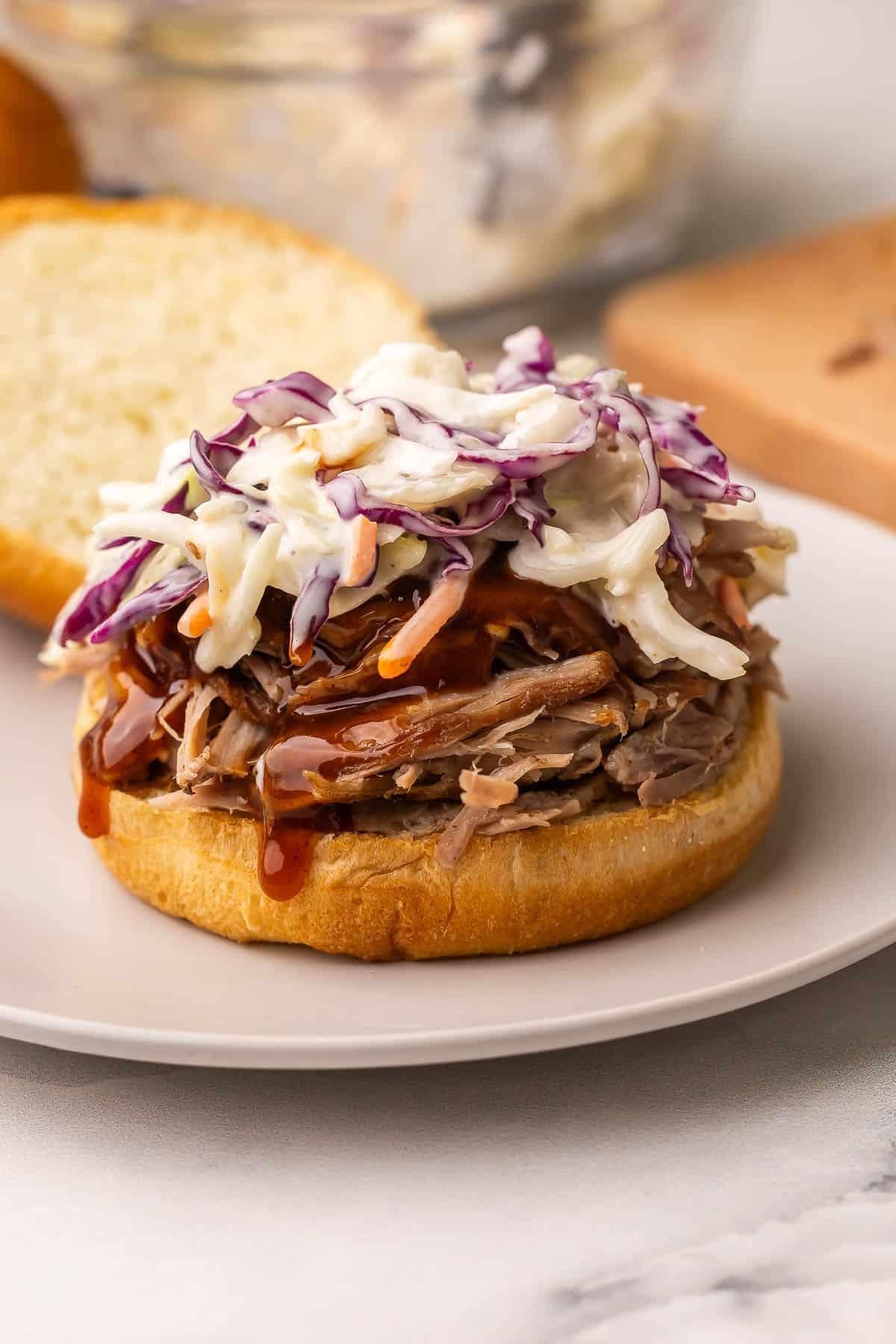 This Oven Pulled Pork recipe gives you the most tender, juicy pulled pork every single time! Seasoned with a bold spice rub and Dr. Pepper for rich, smoky-sweet flavor. #recipe #dinner #pork | pork recipes | pulled pork sandwich | sandwich recipes | barbecue | bbq | potluck | picnic | easy dinner ideas pulled pork sandwich with coleslaw and no top bun.