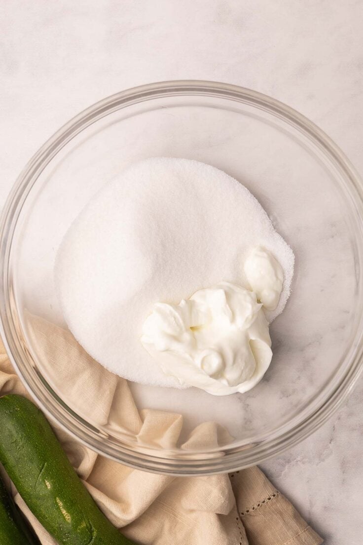a glass mixing bowl with sugar and greek yogurt added.