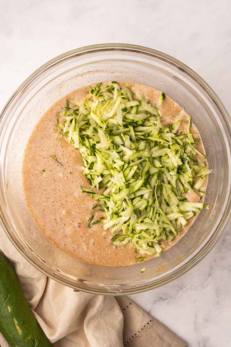 shreeded zucchini added to bowl of mixed ingredients.