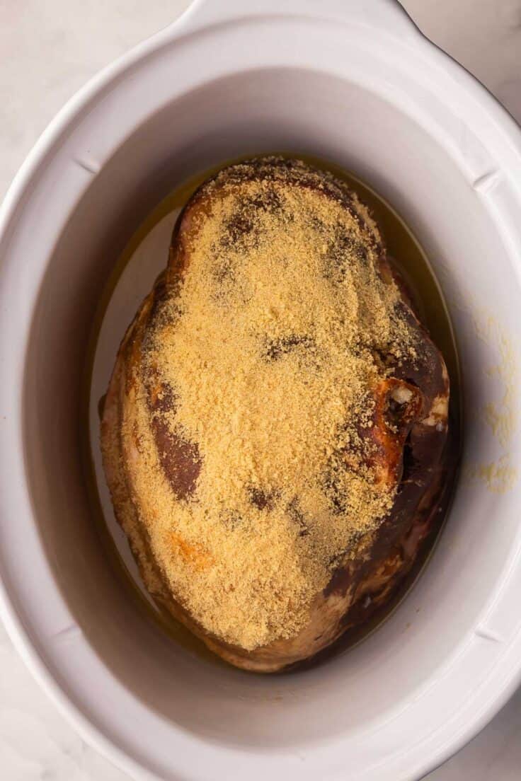 a white crockpot filled with a ham.