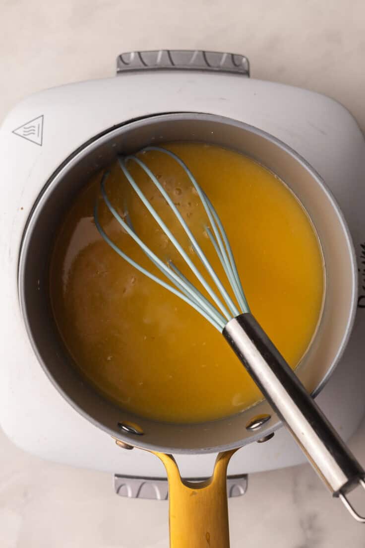 pineapple sauce in a pot with a whisk.