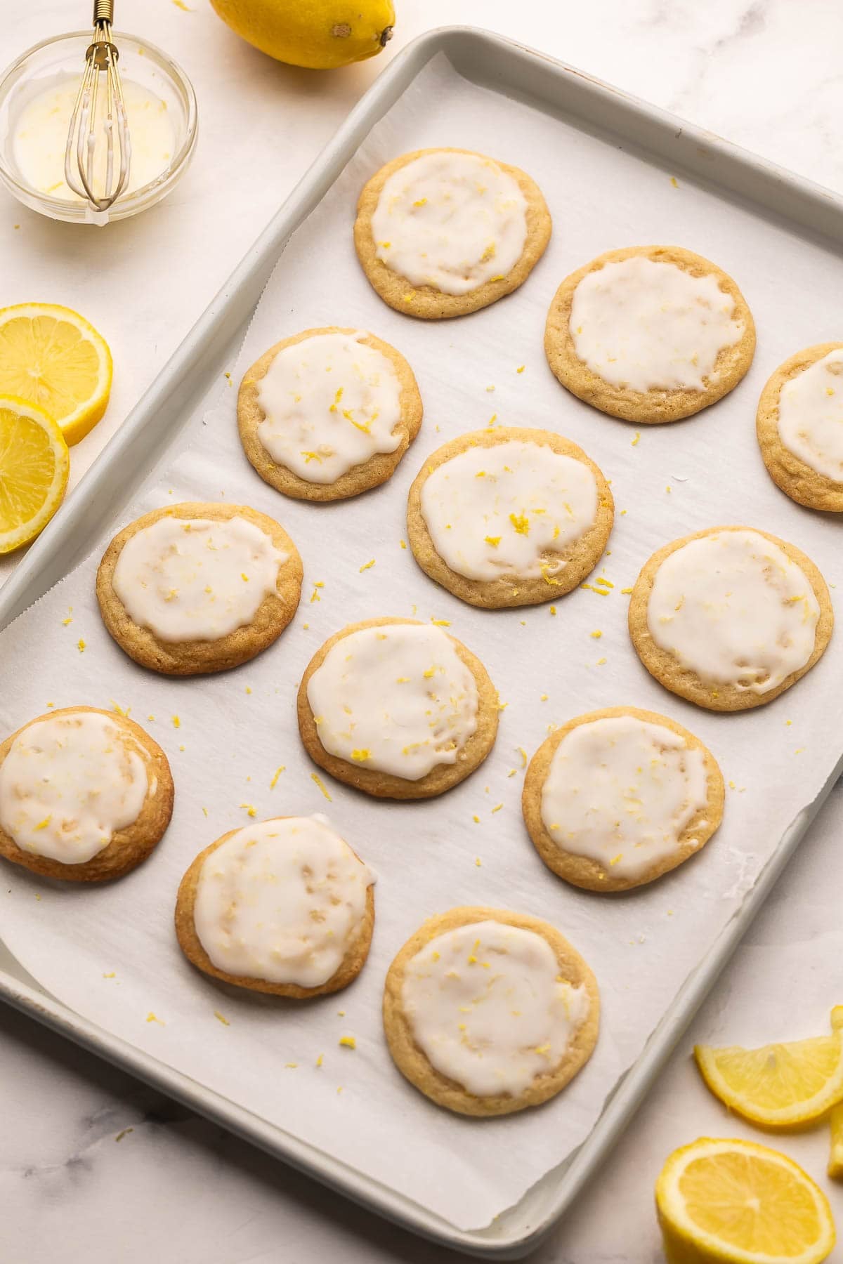 baking sheet lined with parchment with glazed lemon cookies on it.