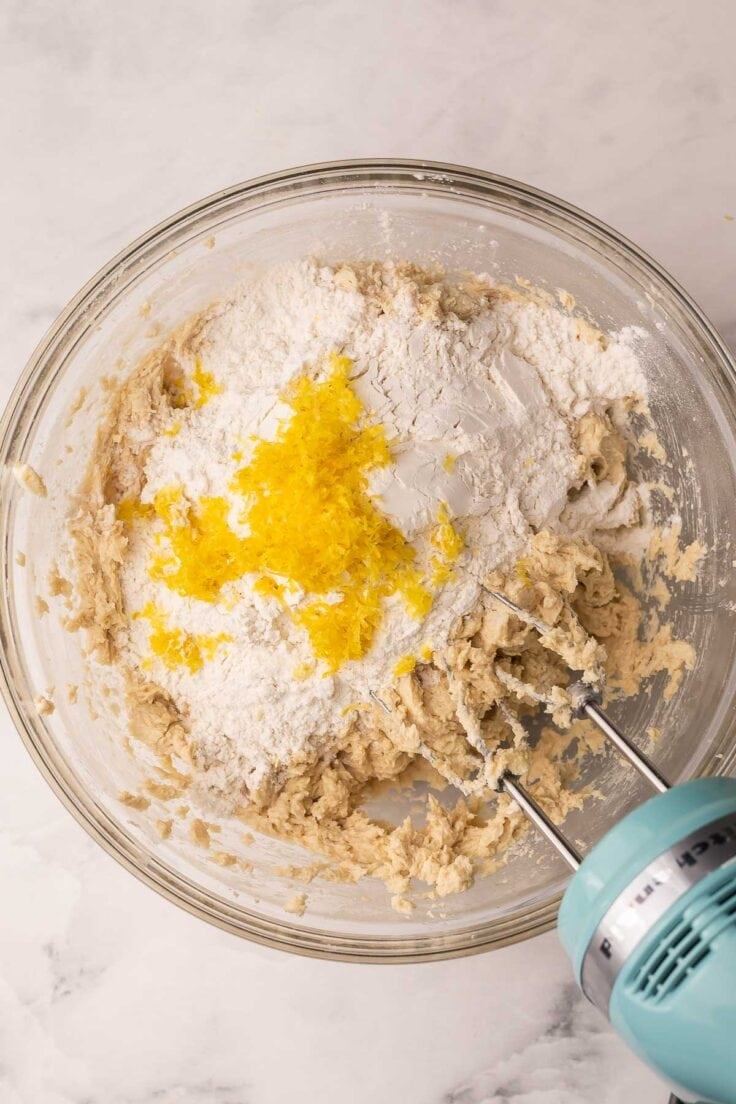 dry ingredients added to cookie dough in glass bowl.