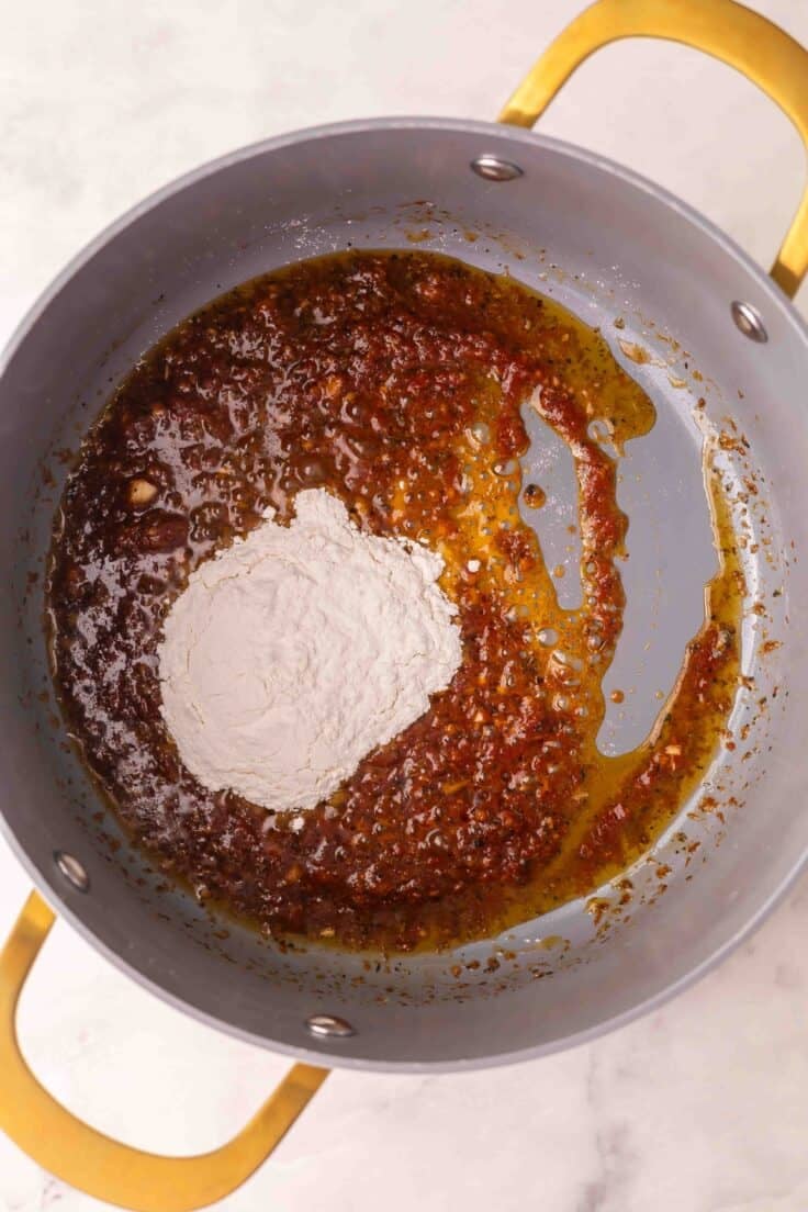 flour added to soup pot with other ingredients.