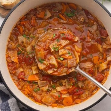 square image of metal ladle scooping cabbage soup from dutch oven.