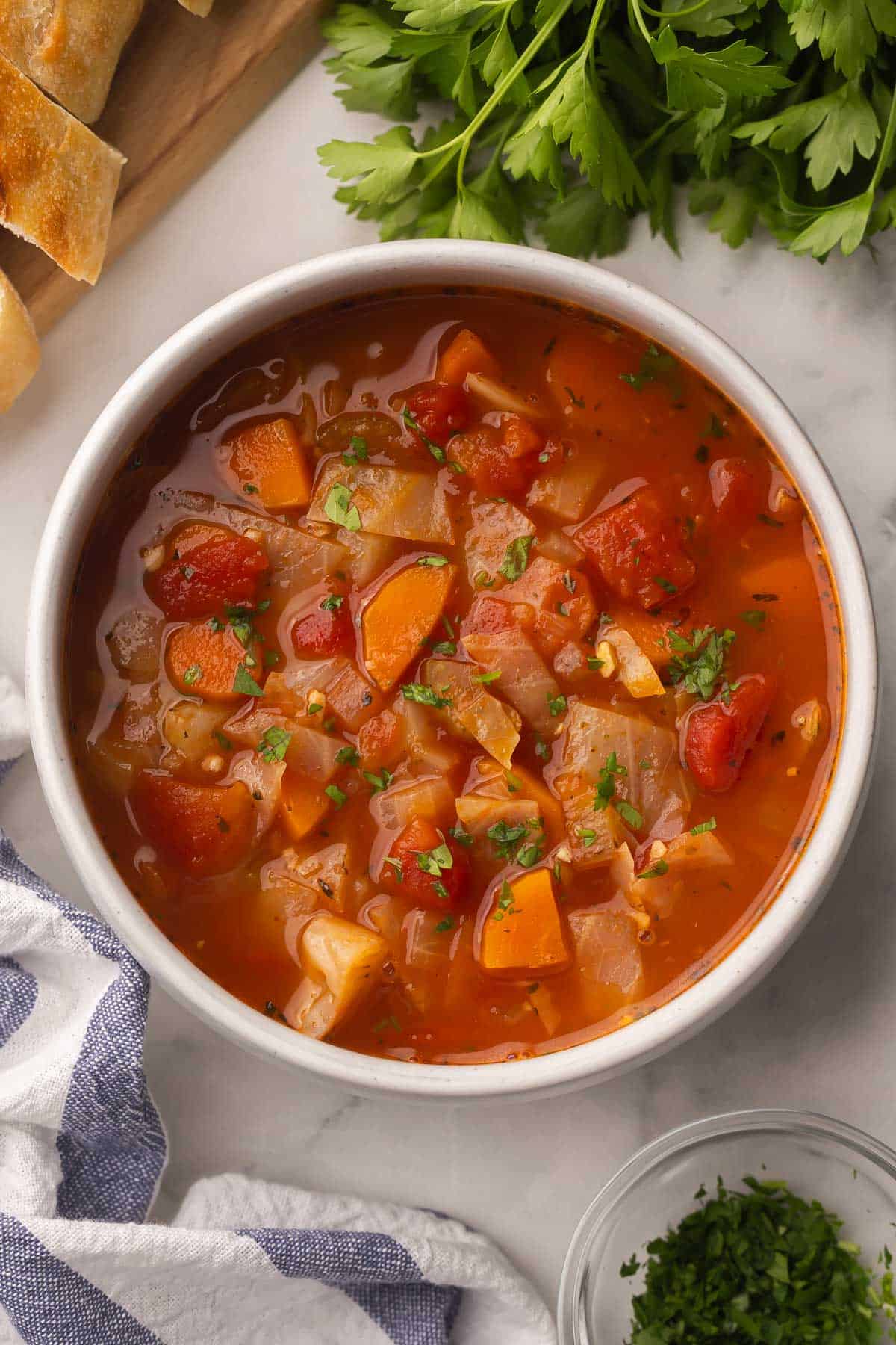 This easy Cabbage Soup is a healthy soup recipe made with just a few ingredients, including cabbage, carrots, onions, celery, and tomatoes. It's vegetarian, gluten-free and full of flavor! #soup #dinner #recipe | soup recipes | comfort food | healthy dinner ideas | dinner recipes | high fiber | cabbage recipes healthy cabbage soup in a bowl with parsley on the side.