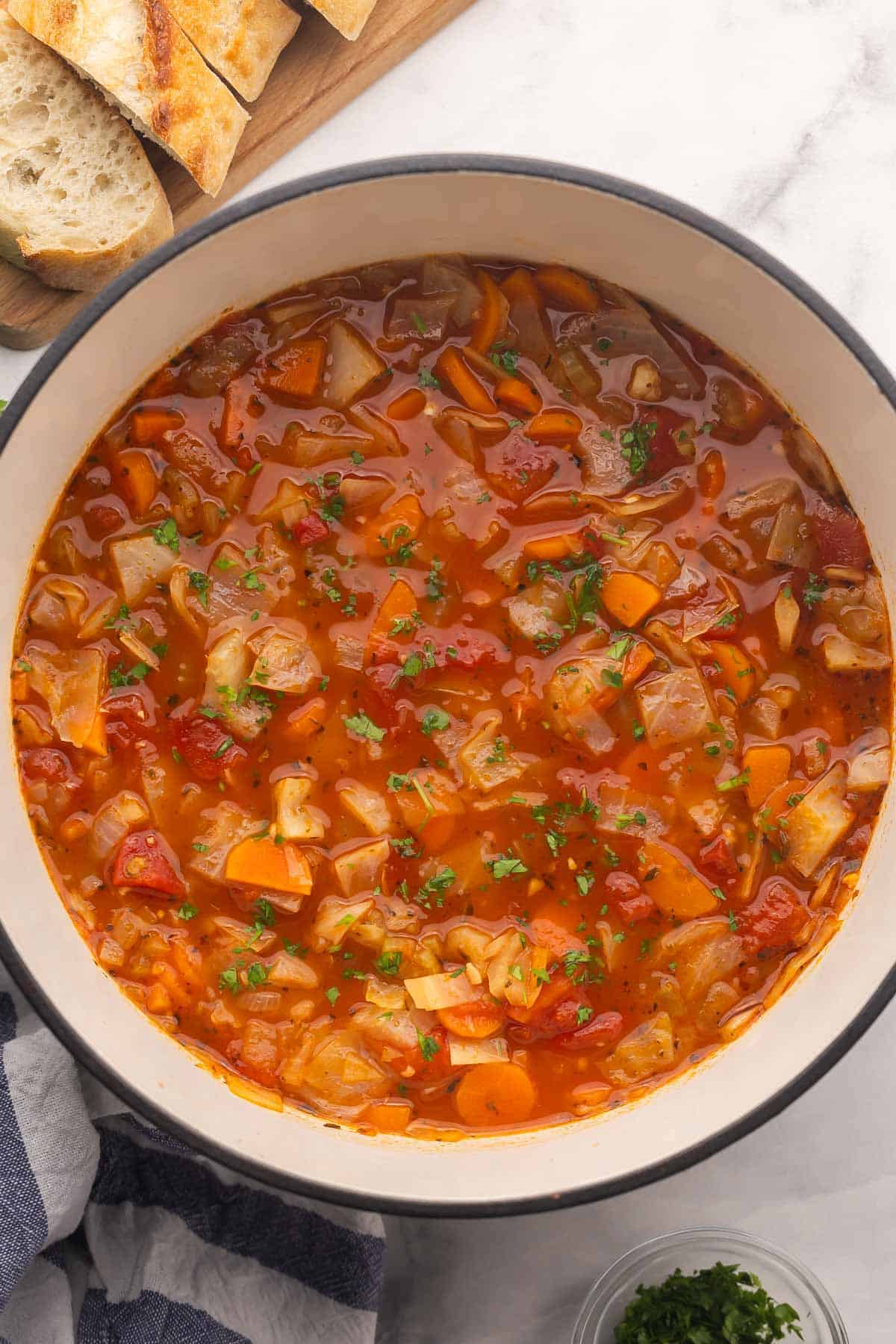 overhead image of cabbage soup in a dutch oven with bread on the side.