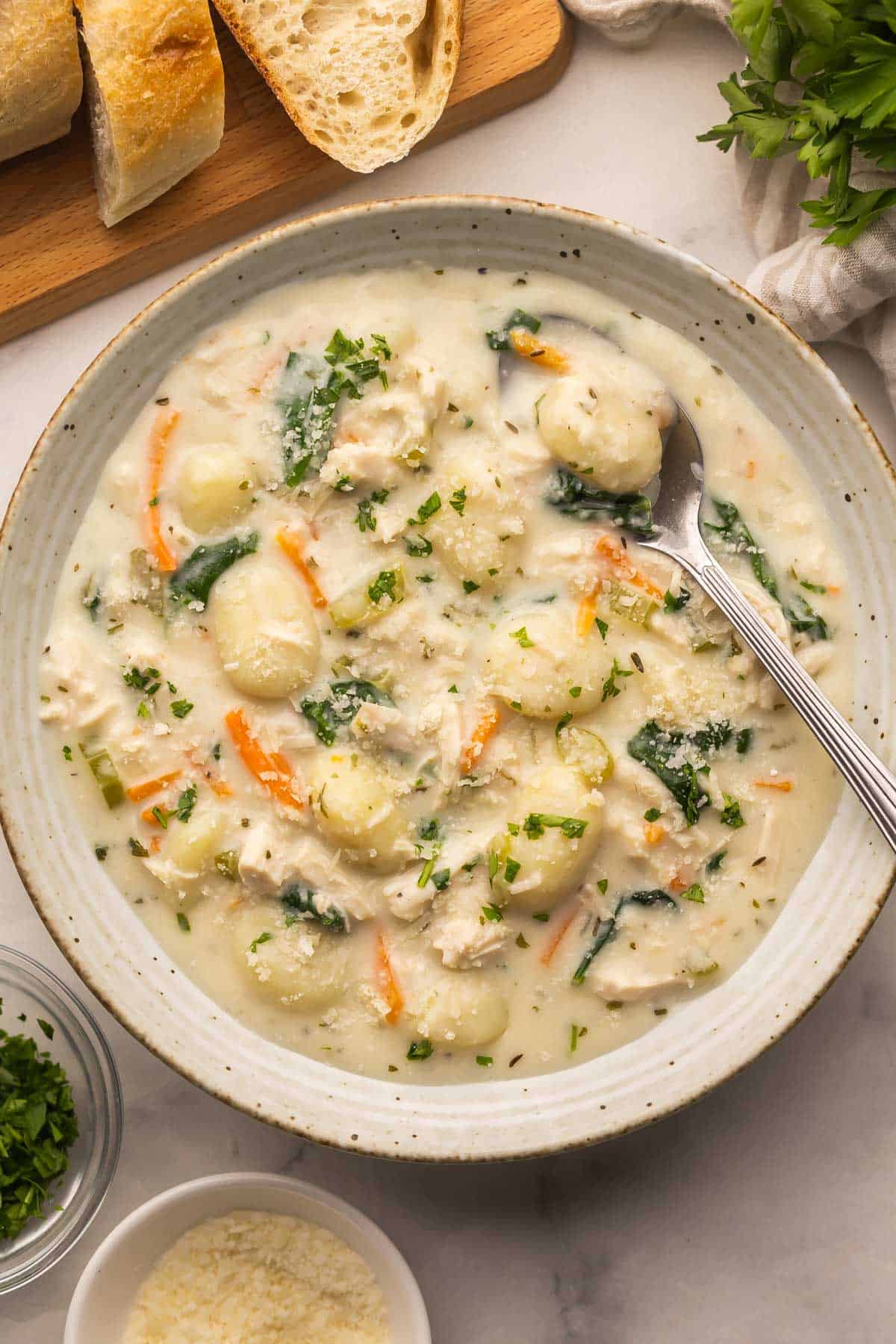 speckled bowl filled with chicken gnocchi soup and a spoon.