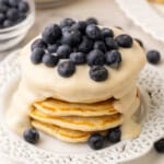 cream sauce and blueberries on top of a stack of pancakes.