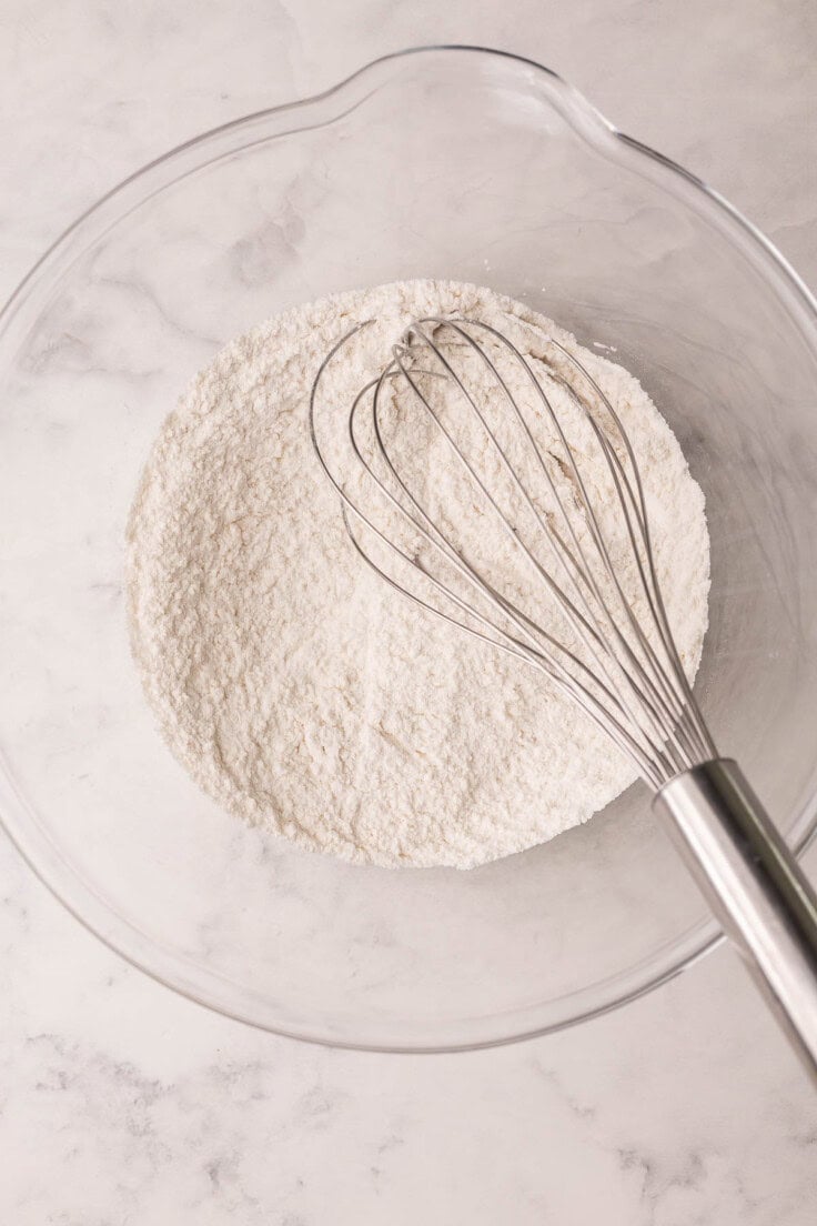 large glass bowl with flour and whisk.