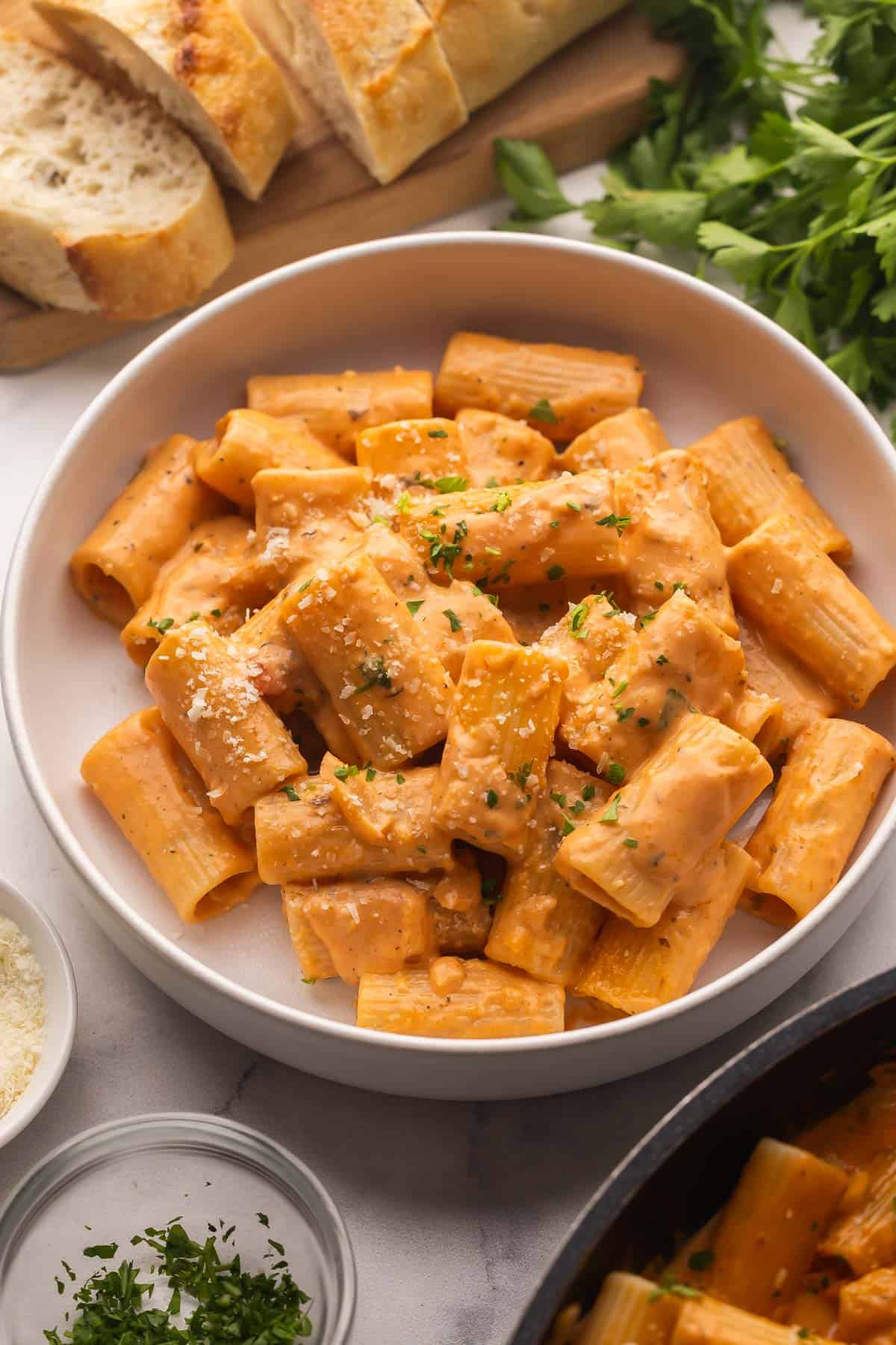 Creamy Tomato Rigatoni Pasta is a 25-minute, family-friendly dinner with rigatoni tossed in a creamy tomato sauce and finished with Parmesan. Simple ingredients, big flavor! #dinner #recipe easy meal ideas | easy recipes | pasta recipes | rigatoni recipe | easy dinner ideas creamy tomato rigatoni pasta in a pasta bowl with parmesan and parsley.