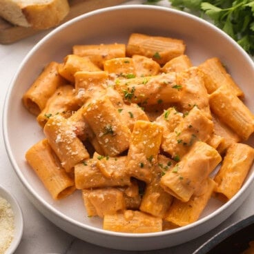 square image of tomato rigatoni pasta in pasta bowl.