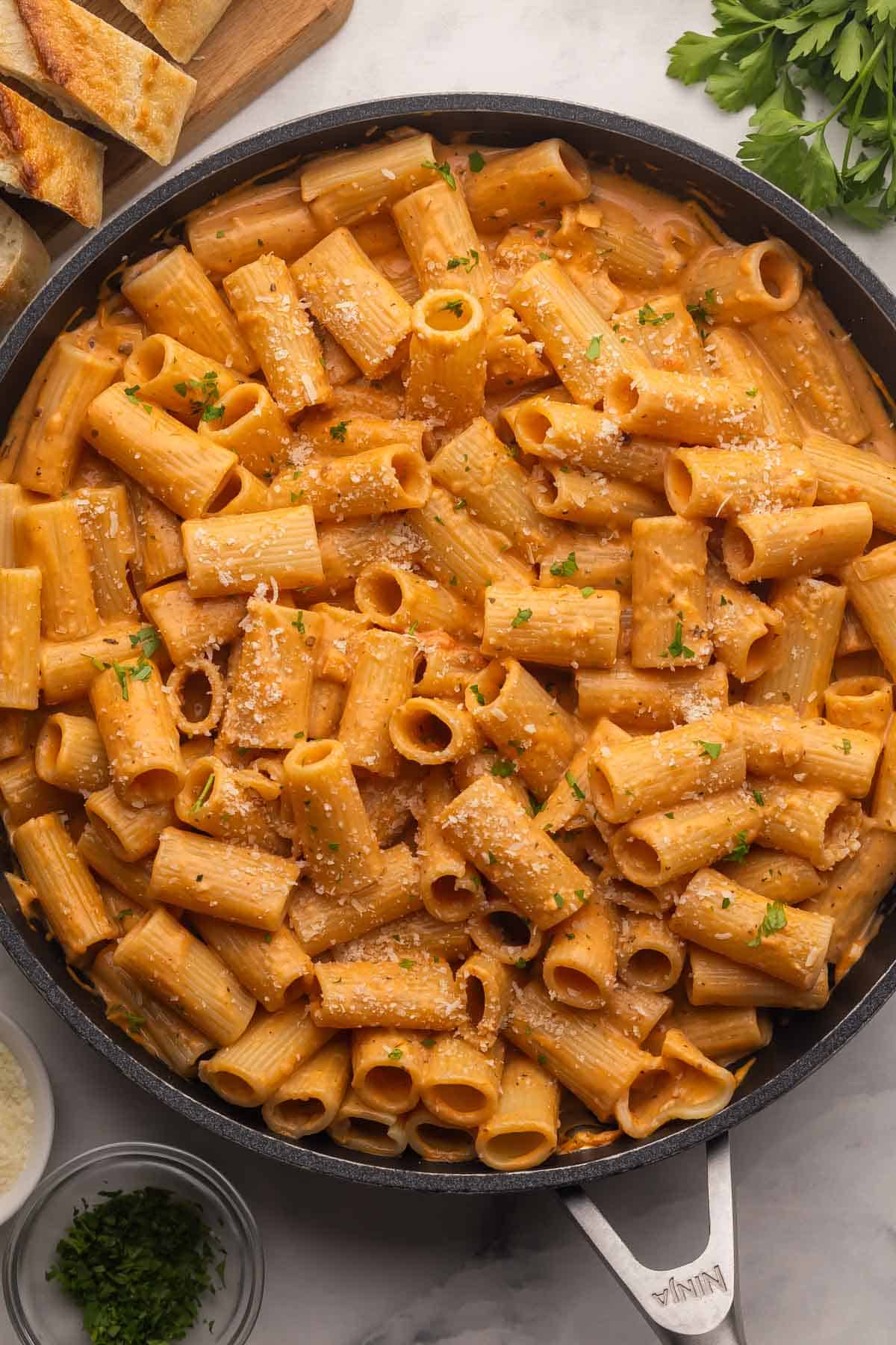 Creamy Tomato Rigatoni Pasta is a 25-minute, family-friendly dinner with rigatoni tossed in a creamy tomato sauce and finished with Parmesan. Simple ingredients, big flavor! #dinner #recipe easy meal ideas | easy recipes | pasta recipes | rigatoni recipe | easy dinner ideas overhead image of creamy tomato rigatoni pasta recipe in black skillet.