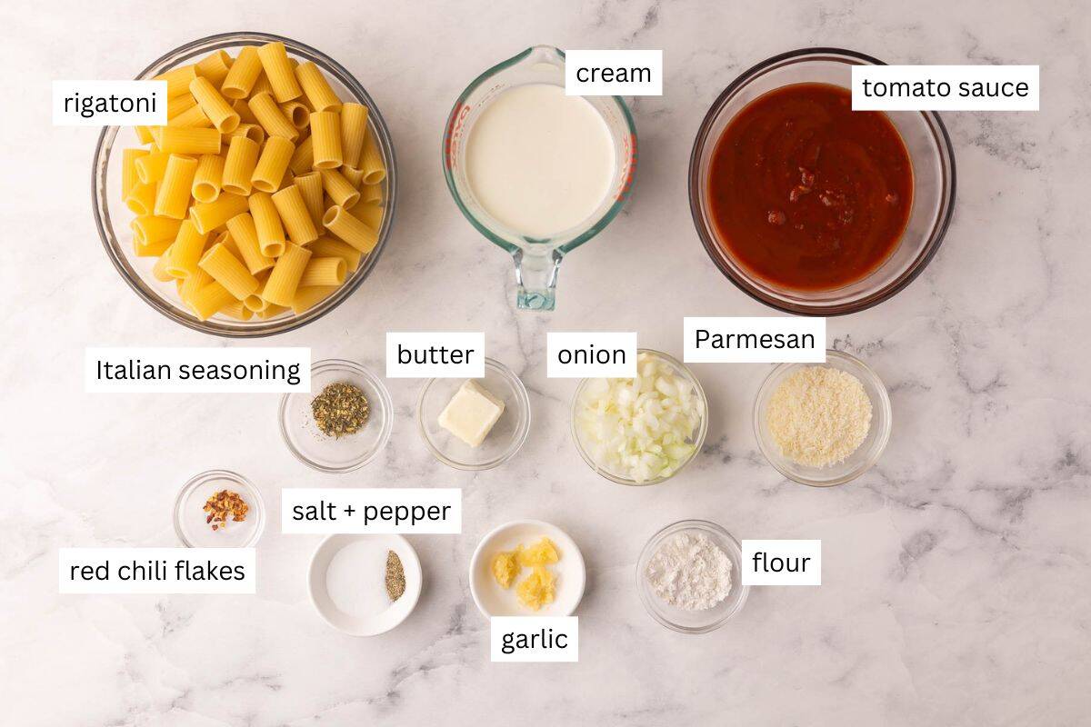 Creamy Tomato Rigatoni Pasta is a 25-minute, family-friendly dinner with rigatoni tossed in a creamy tomato sauce and finished with Parmesan. Simple ingredients, big flavor! #dinner #recipe easy meal ideas | easy recipes | pasta recipes | rigatoni recipe | easy dinner ideas ingredients to make creamy tomato rigatoni pasta on white background.