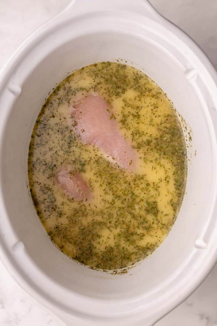 chicken added into white crockpot.