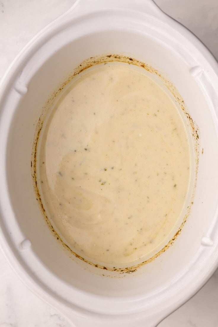 white crockpot full of creamy sauce.