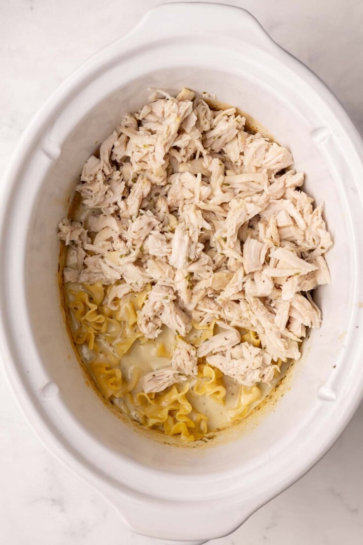 shredded chicken added to white crockpot.