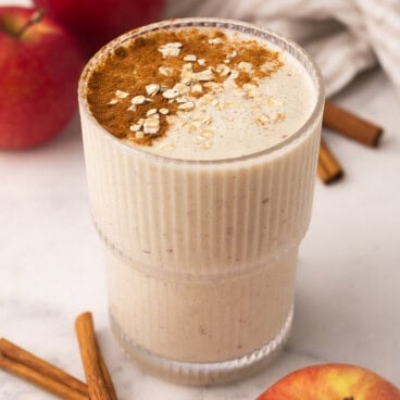apple crisp smoothie in a glass cup with sprinkled cinnamon on top.