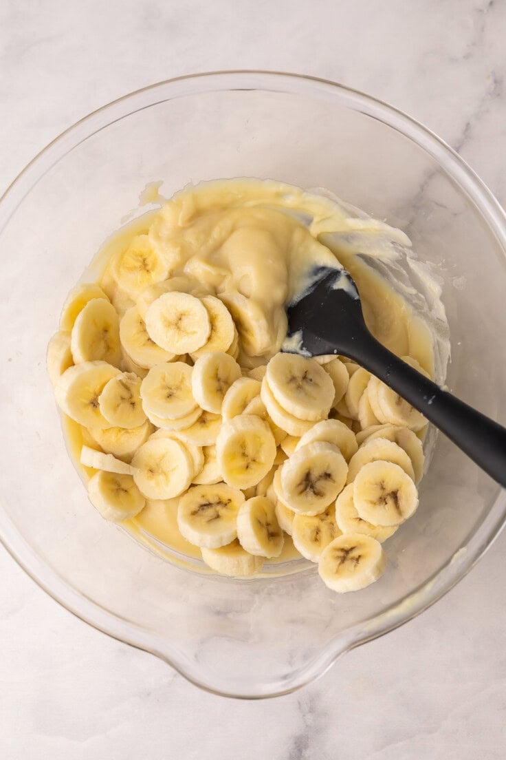sliced bananas in glass mixing bowl with other ingredients.