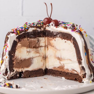 brownie mountain ice cream cake on a white plate with some pieces cut out of it.