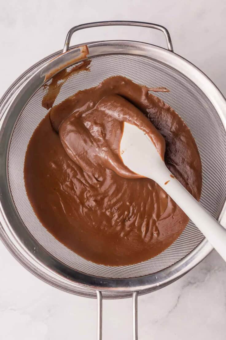 chocolate filling in strainer with spatula.