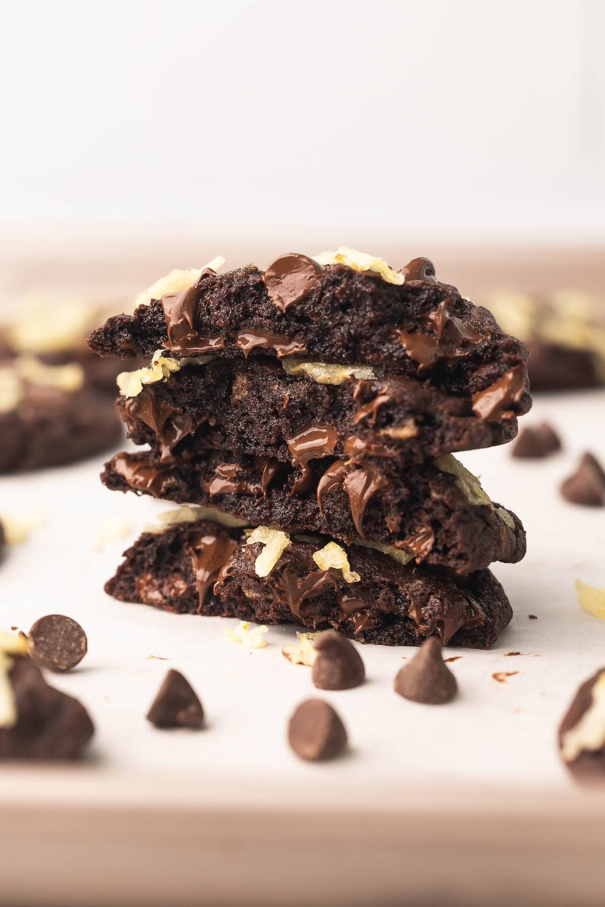 Double Chocolate Potato Chip Cookies are rich, fudgy chocolate cookies packed with chocolate chips and salty potato chips. No need to chill the dough, and they're ready in 25 minutes! #cookie #cookies #chocolate | chocolate cookies | sweet and salty | cookie recipes | baking recipes | easy dessert recipes | a stack of double chocolate potato chips cookies with chocolate chips beside.