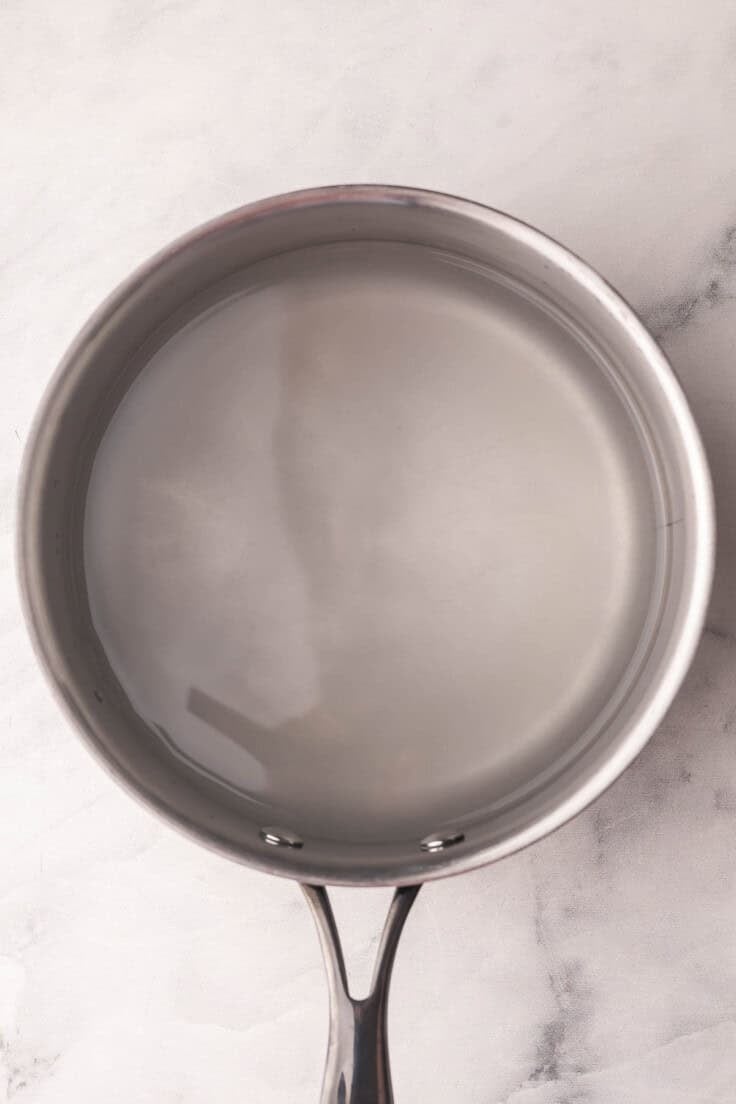 pot of salted water on marble surface.