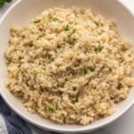 cooked brown rice in a bowl topped with chopped parsley.
