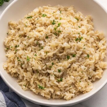 cooked brown rice in a bowl topped with chopped parsley.