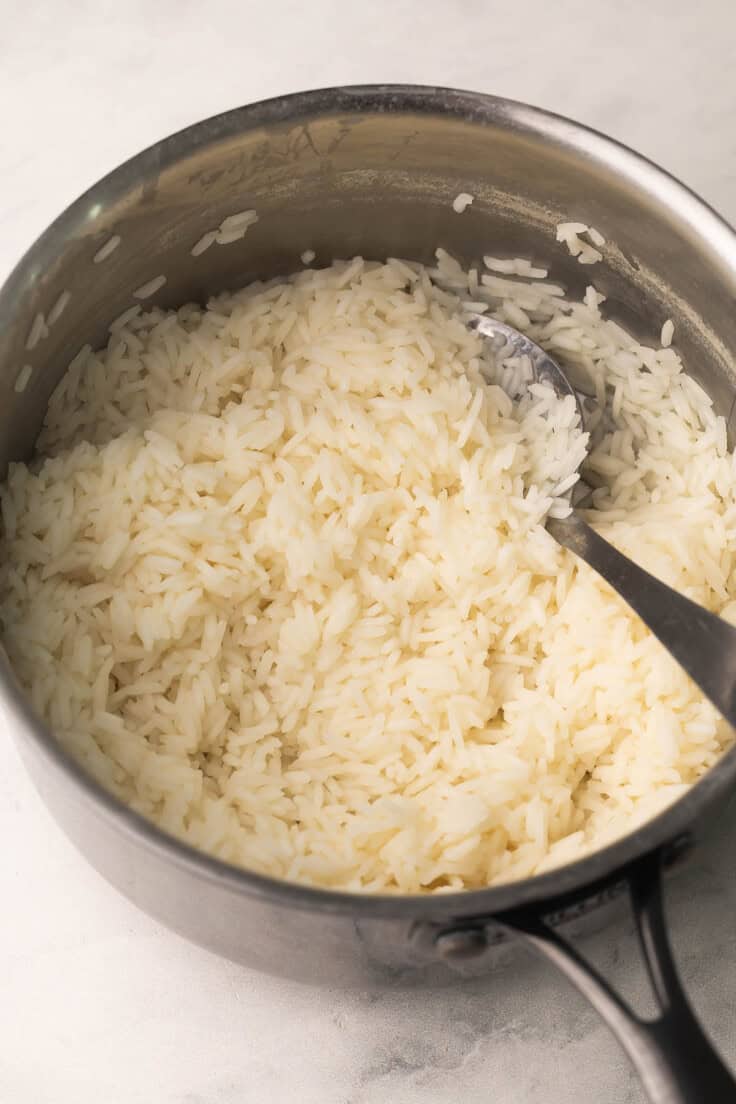 cooked long grain white rice in a stainless steel pot.